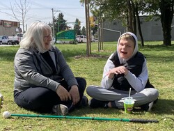 Student and Intervenor sitting on the grass smiling at one another. 